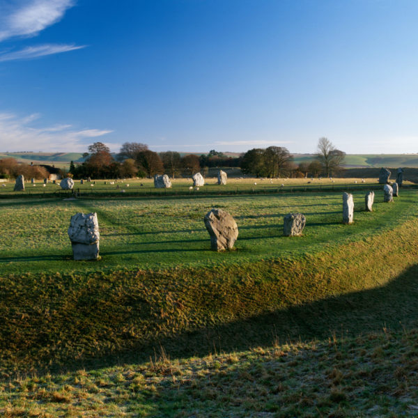 A ring of standing stones on grass surrounded by a ditch