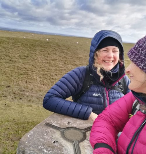 two women standing at a trig point