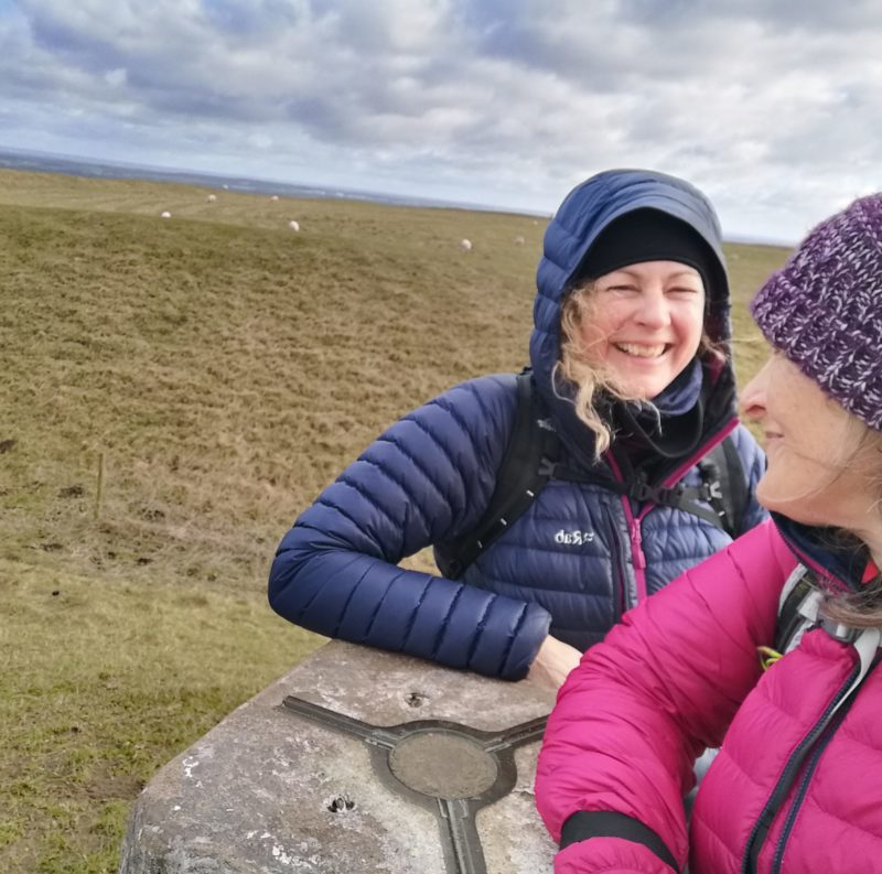 two women standing at a trig point