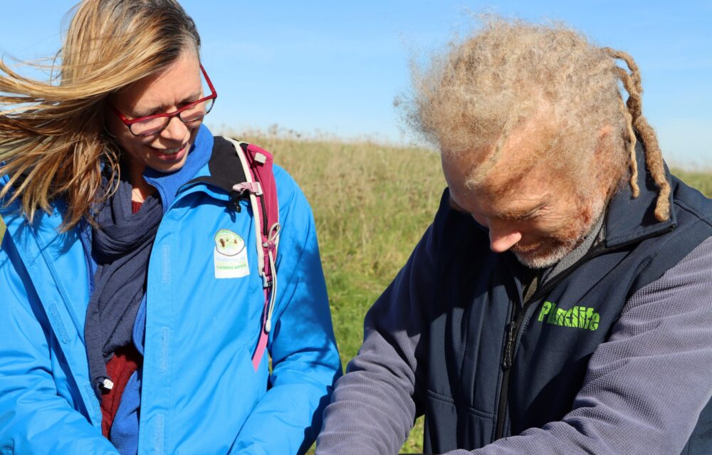 Two people are looking with interest at something out of frame. One of the two is a Plantlife team member. Two people are looking with interest at something out of frame. One of the two is a Plantlife team member.