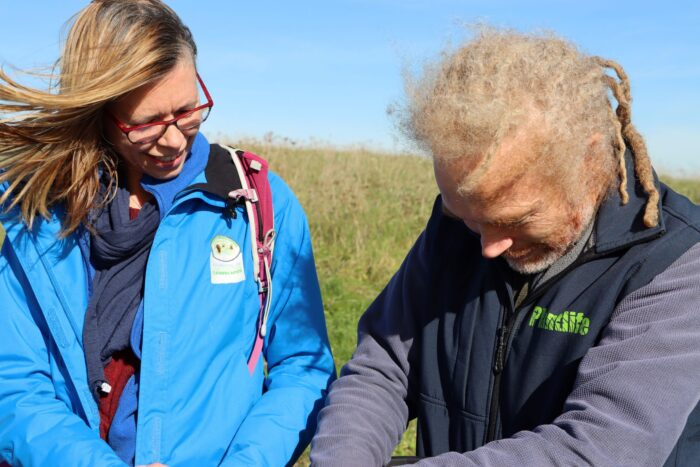 Two people are looking with interest at something out of frame. One of the two is a Plantlife team member.
