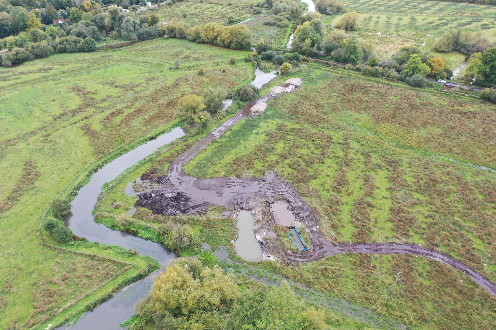 An aerial view of fields, a river and hedging. There is evidence of groundworks to the right of the river.